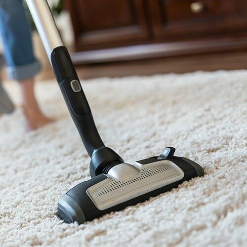 Woman using a vacuum cleaner while cleaning | New York Carpets & Flooring