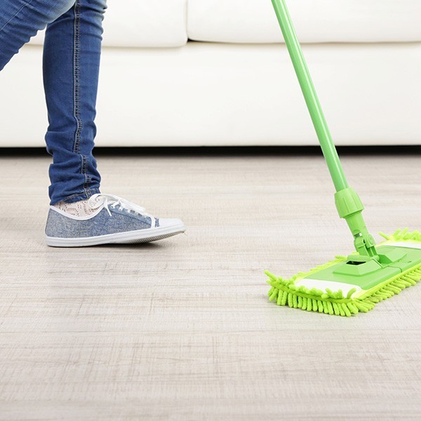 Woman with mop cleaning wooden floor | New York Carpets & Flooring